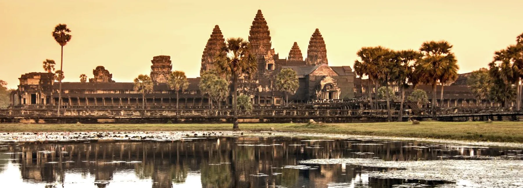 Panoramic view of Angkor Wat temple towers reflecting across the lotus pond in Siem Reap, Cambodia.