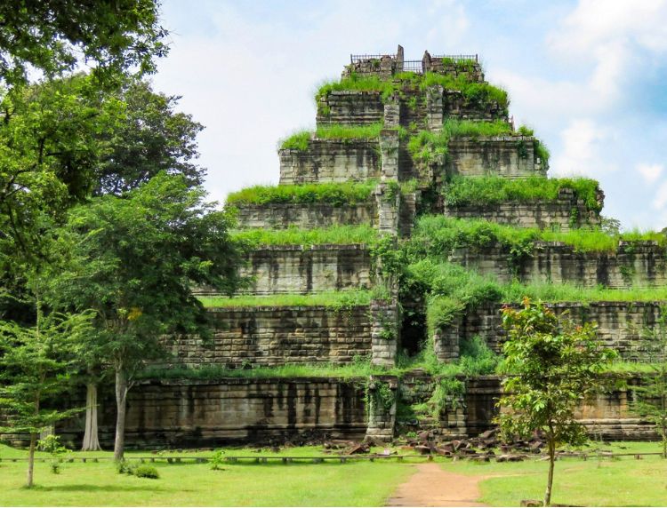 The ancient seven-tiered stone pyramid of Prasat Prang at Koh Ker, Cambodia, partially covered in green moss and grass.
