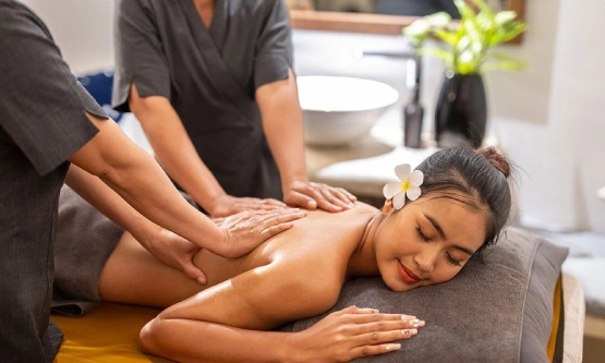 Four-hands back massage treatment for a woman relaxing in a luxury spa setting.
