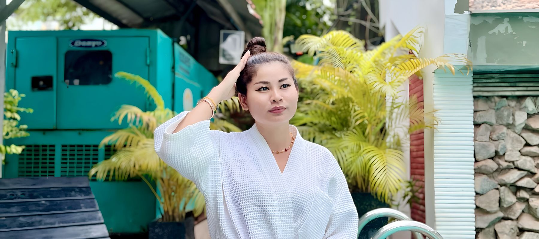 Guest wearing a white waffle-weave bathrobe posing outdoors by a hotel pool setup.